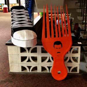 Large sculptures of a converse high-top sneaker (left) and a red hair pick with the outline of Freddy Mercury's face